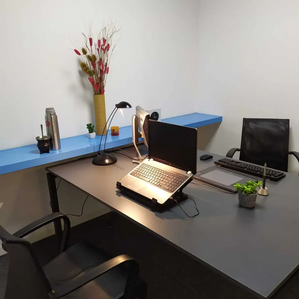 Escritorio de oficina privada con notebook, teclado y lámpara