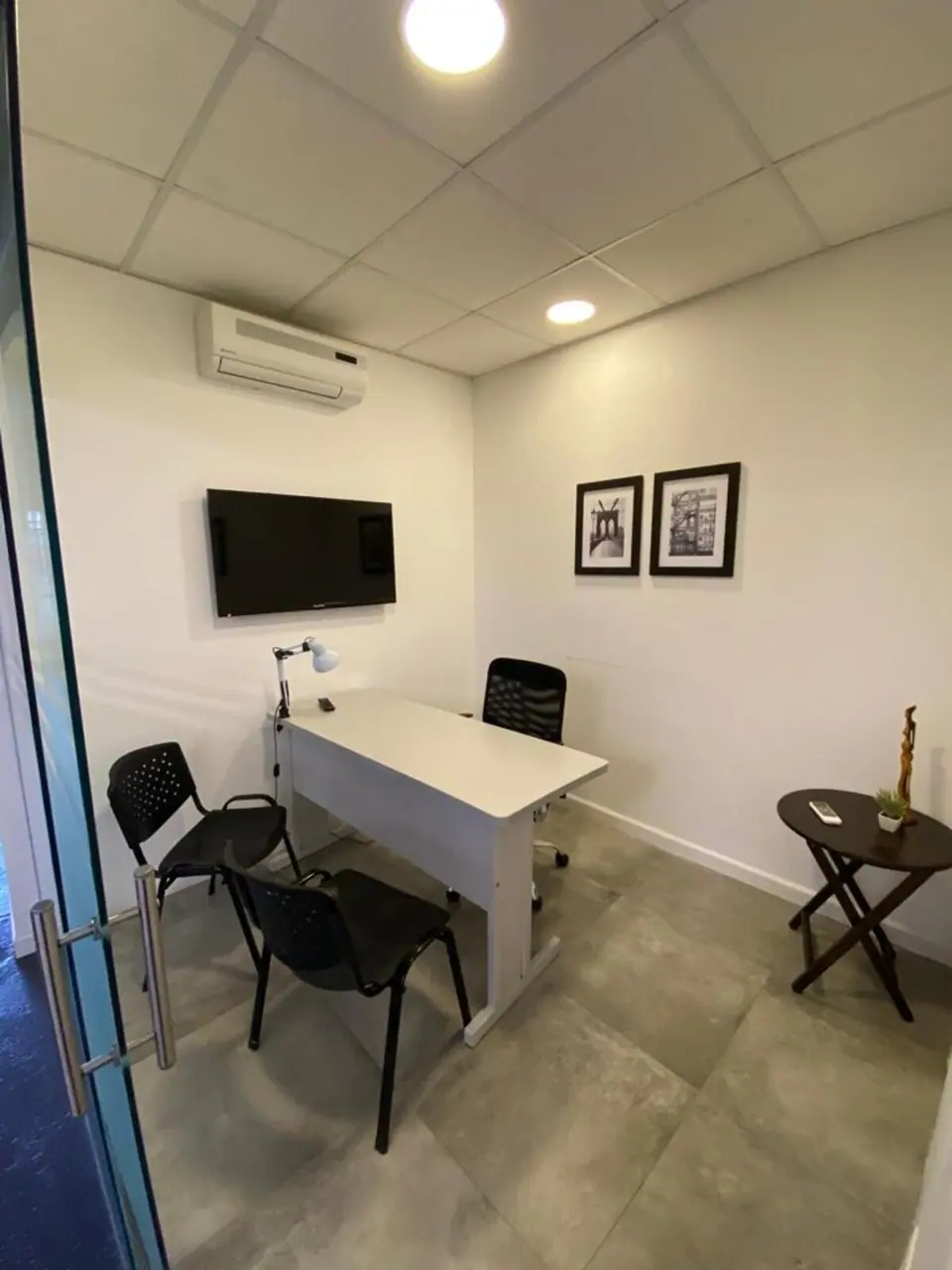 Oficina privada con escritorio, sillas, televisor y aire acondicionado
